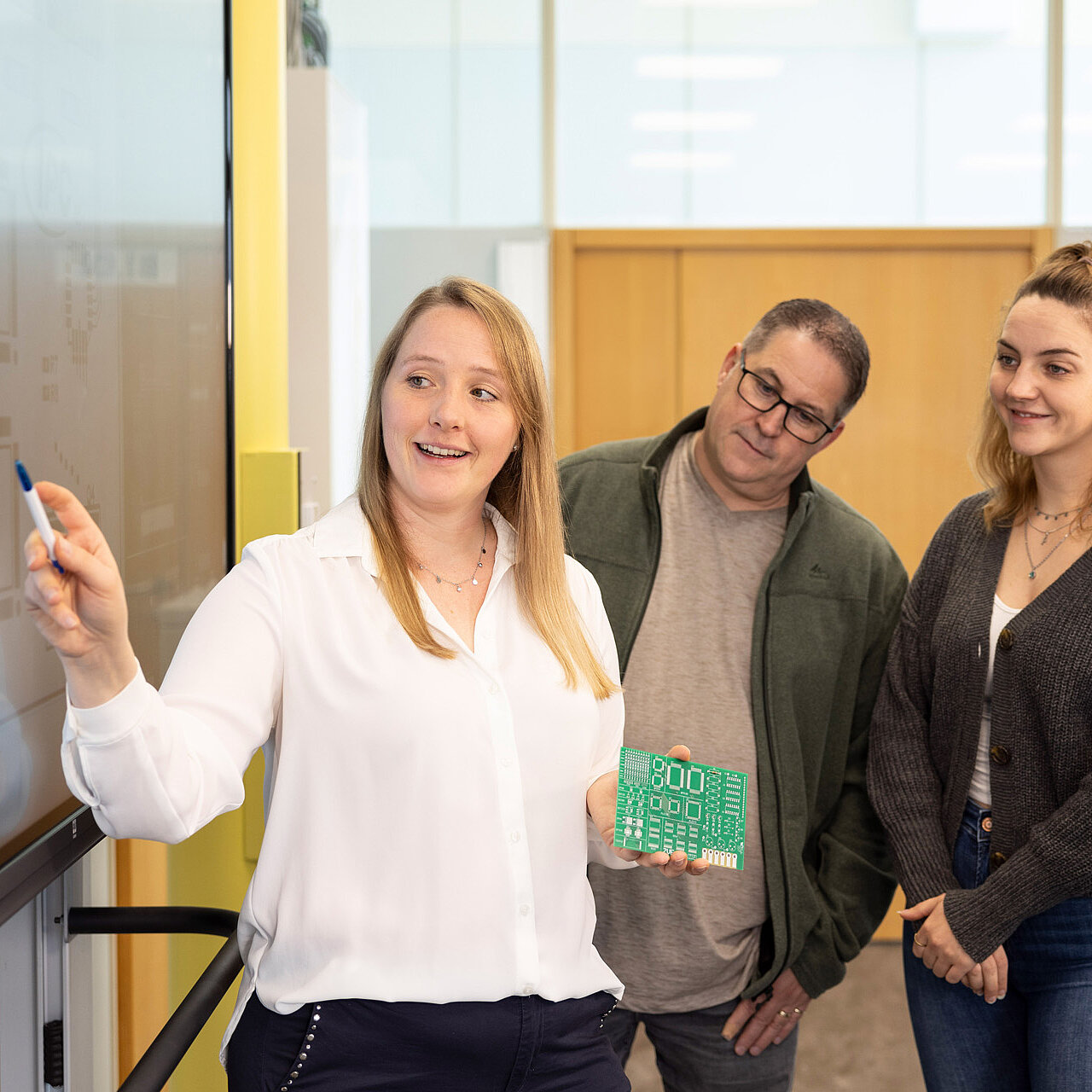 Lisa Greck erklärt Teilnehmern eines Lötkurses ein Lötplatine