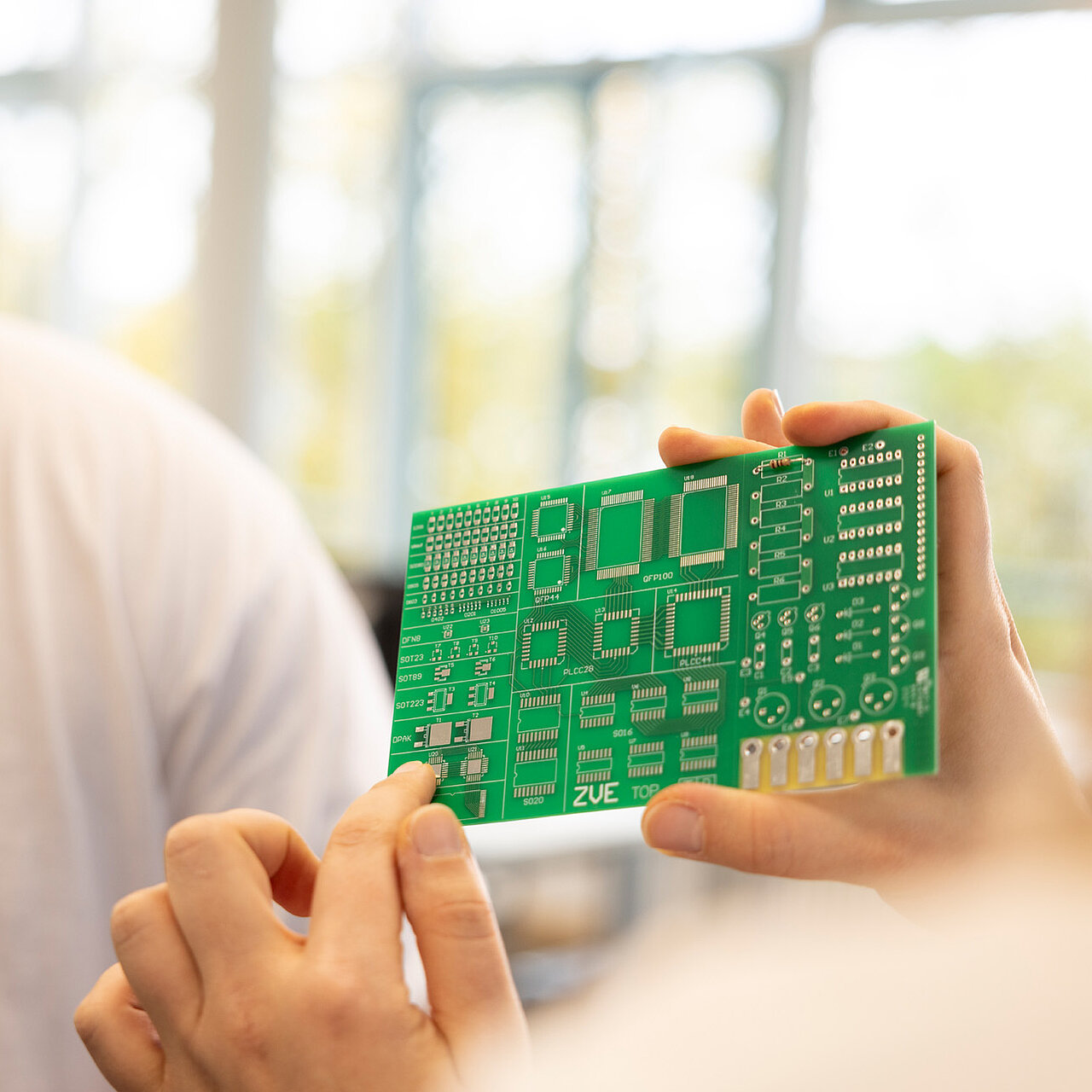 Eine Frau zeigt mit dem Finger auf die Anschlüsse einer Lötplatine